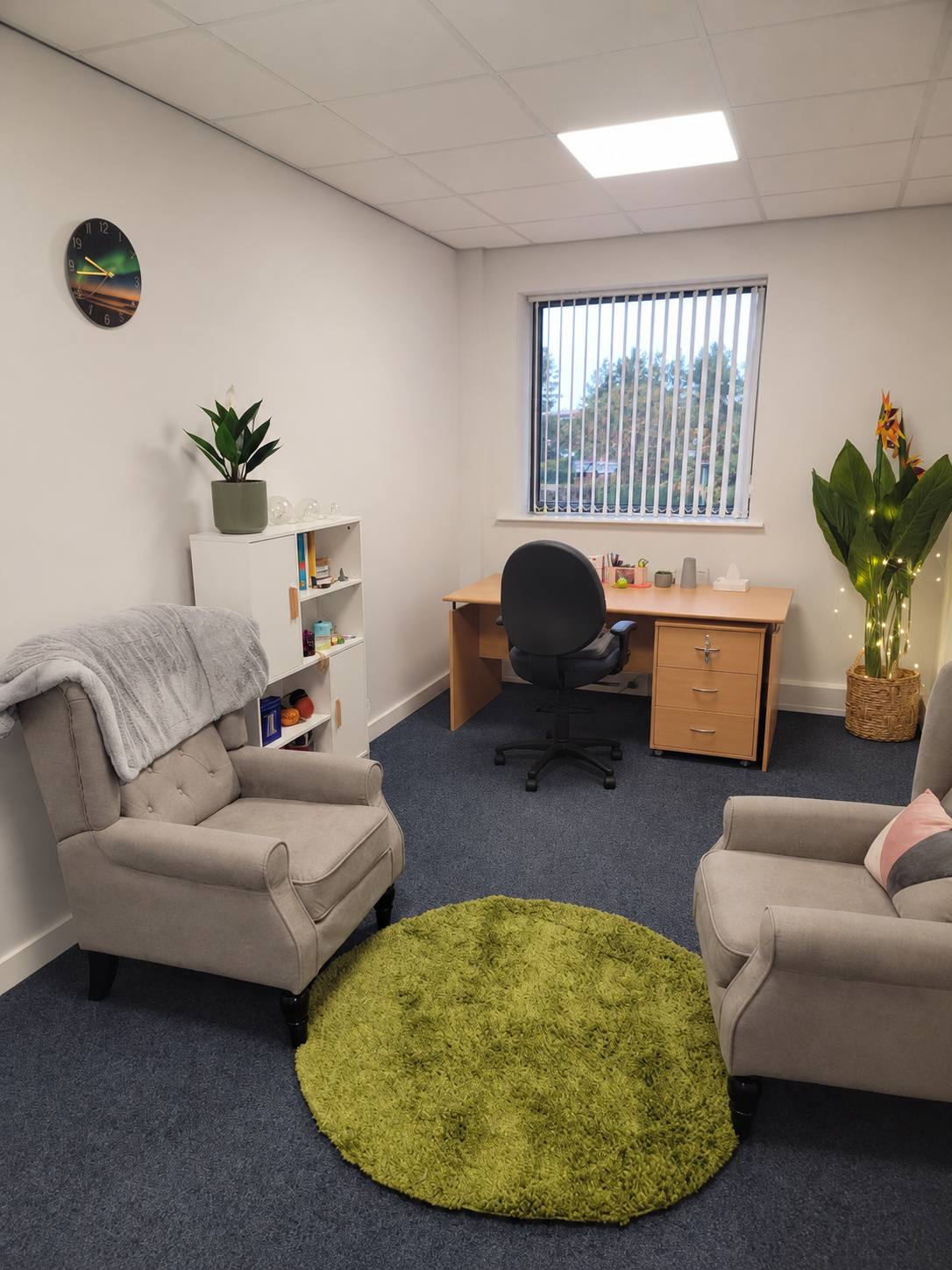 Two comfortable armchairs and a leafy plant in Kerry’s counselling room